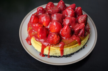 Baked strawberry cheesecake with fresh strawberries from the garden and dripping coulis, slice of cake, top view
