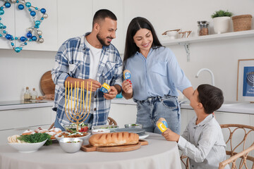 Happy family with dreidels having dinner in festive kitchen. Hanukkah celebration
