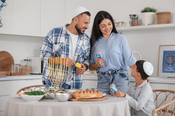 Happy family with dreidels having dinner in festive kitchen. Hanukkah celebration