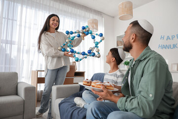 Happy family with donuts and David star at home. Hanukkah celebration