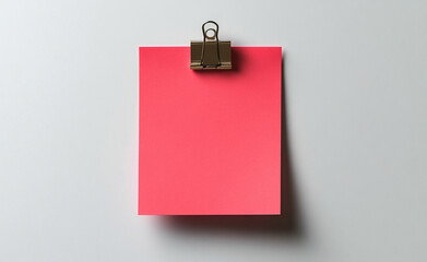 Minimalistic image of a red square paper held by a metal binder clip against a plain white background, ideal for notes or design mockups.
