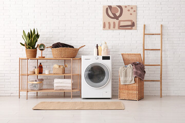 Modern washing machine, shelving unit, basket with laundry and ladder in room