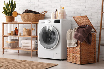 Modern washing machine, shelving unit and basket with laundry in room