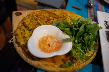 Crispy Vietnamese pancake served with fresh herbs and dipping sauce, vibrant traditional flavors