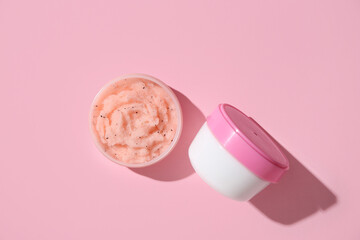 Jars with natural body scrubs on pink background