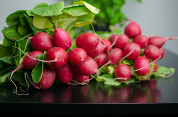 Freshly harvested red radish with green leaves on the black table