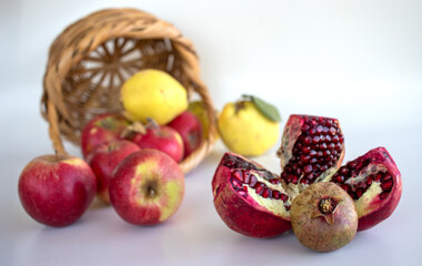 quince, apple, pomegranate, white background in the wicker basket. autumn
