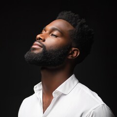 Obraz premium A striking portrait of a thoughtful man with a beard, wearing a white shirt against a dark backdrop.