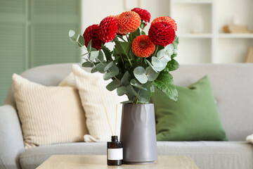 Dahlia flowers and aroma diffuser on coffee table in interior of living room
