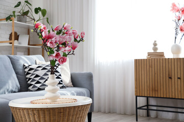 Vase with magnolia flowers on table in living room