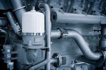 Large  piston gas engine electric generator with many valves and pipes. The engine is orange and has many valves.