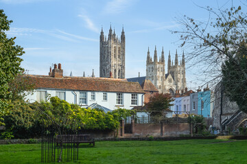 Canterbury cathedral seen from a park in the city over the roof tops of houses.