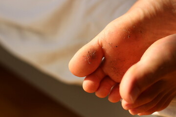 Resting on soft sheets, a pair of dirty feet bring a playful and relaxed vibe