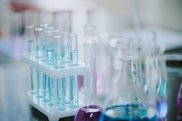 Assorted laboratory test tubes holding various colored liquids on table in scientific setting, suggesting scientific experimentation and research work