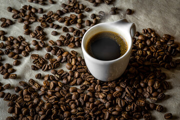 Xícara com um saboroso cafezinho em meio aos grãos de café. 