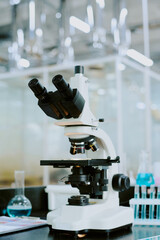 Close-up of advanced microscope in a high-tech laboratory environment featuring equipment and glass containers in the background