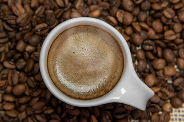 Xícara com um saboroso cafezinho em meio aos grãos de café. 