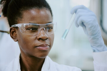 Lab technician examining test tube with protective glasses during chemical process. Showing focus...