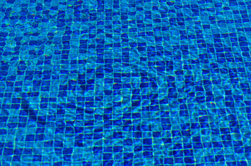 Crystal clear blue swimming pool tiles reflecting sunlight on a warm summer afternoon