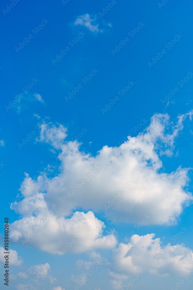 Wall mural this captivating stock image features a wide blue sky filled with fluffy white clouds. the serene at