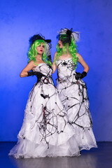 Two girls in scary wedding dresses with black web, green hair and head decorations. Scary Halloween...