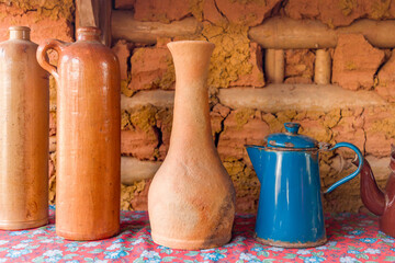 Antique tea pot and vase on table with clay wall in background