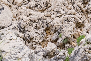 The image presents a close-up view of a weathered rock face characterized by cracks and ledges, showcasing its rough texture and natural beauty from a low angle perspective.