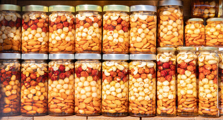 Colorful jars filled with a delightful assortment of nuts and dried fruits arranged neatly on shelves in a vibrant market
