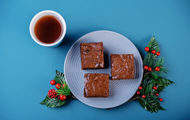 Dark chocolate brownie cakes in a plate on a blue background for Christmas holidays