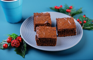 Dark chocolate brownie cakes in a plate on a blue background for Christmas holidays