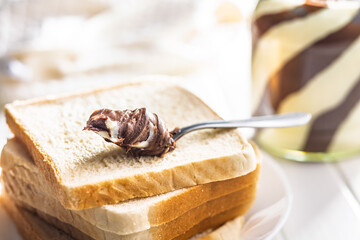 Chocolate cream spread in spoon on bread.