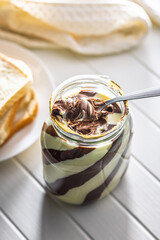 Chocolate cream spread on spoon in jar.