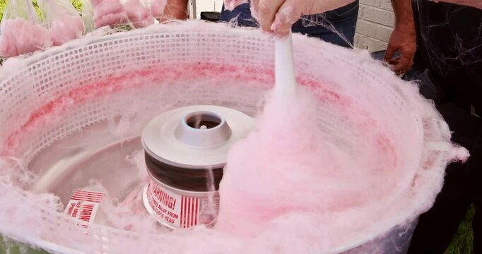 Delicious treat is prepared outdoors using machine pan for making pink cotton candy