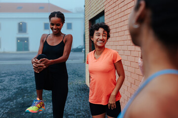 Group of female athletes stretching together before running in the city