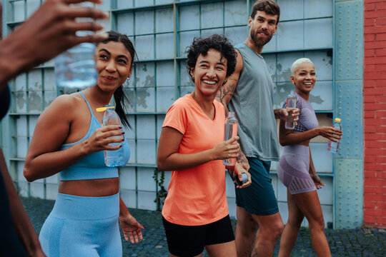 Group of diverse athletes hydrating after an urban workout session
