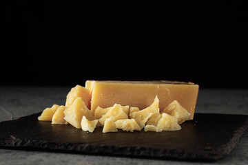 Authentic Italian Parmigiano Reggiano: Aged Cheese Slice on Black and Wooden Backgrounds