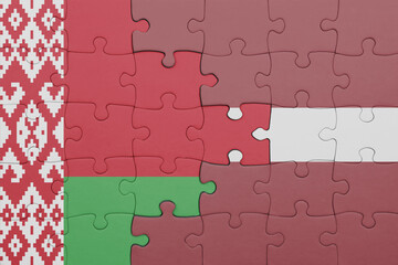 puzzle with the colourful national flag of belarus and flag of latvia .