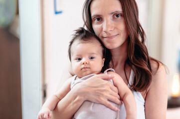 A mother is holding and hugging her baby daughter 