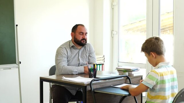 Male teacher speaks with teenager boy at school