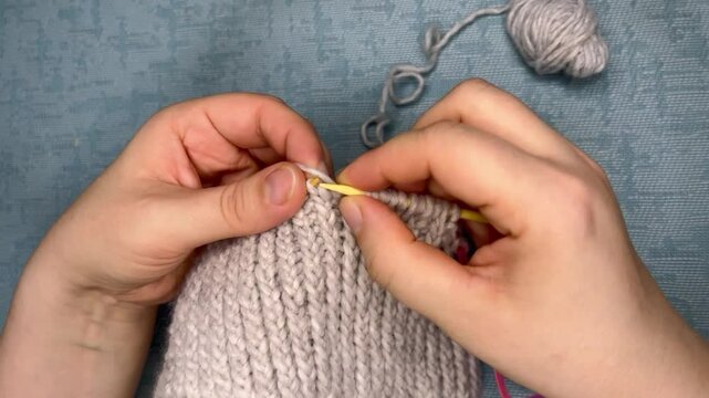 knitting process of gray wool hat with circular bamboo knitting needles. needlework handmade . top view