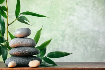 Fototapeta premium Zen stone stack with bamboo leaves on wooden table, serene spa concept banner with green background and ample copy space, capturing tranquility in boho style with smooth natural light.