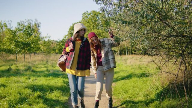 Two close friends are enjoying a sunny day outdoors, surrounded by nature. They bond while walking a scenic path, experiencing joy and laughter during this memorable spring weekend