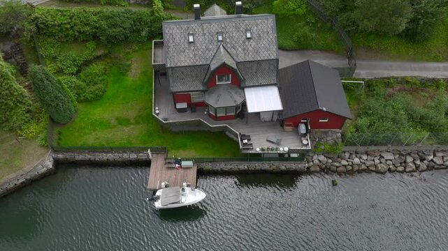 Typical Norwegian House with Boat Pier on the Fjord Coast in Odda With Mountains on Background, Aerial Drone Shot.