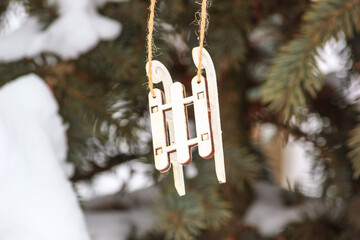 Cute decoration in the form of a wooden sledge on a Christmas tree, outside next to the house, closeup