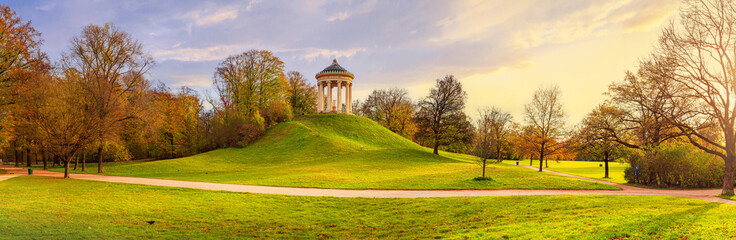 Autumn landscape, panorama, banner - view of the Englischer Garten public park with paths and circular colonnade on the hill, Munich, Bavaria, Germany
