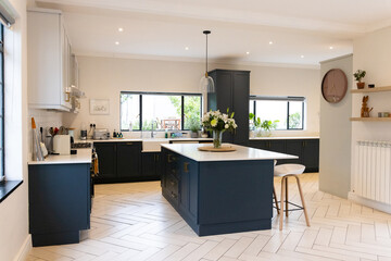 Modern kitchen with navy cabinets and island, featuring elegant floral centerpiece, at home