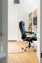 Cozy home office with black chair and bookshelf, ready for work