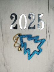 New year 2025 silver numbers on gray wooden background, Christmas tree background
