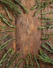 Fresh rosemary and thyme sprigs arranged around a rustic wooden background.