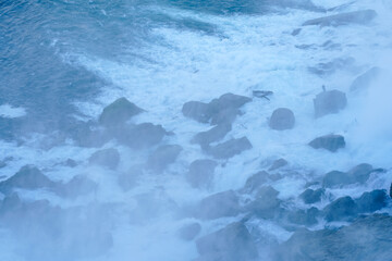 Beautiful autumn day at Niagara Falls, America. Large rocks at the base of the waterfall. Misty scene.